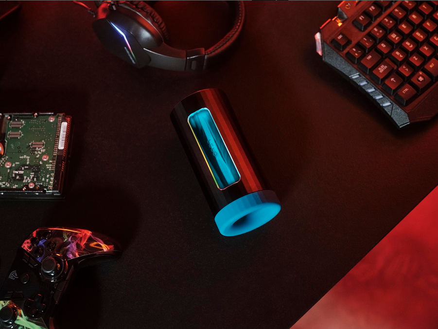 Glowing cylindrical masturbator on a dark surface with computer hardware components.