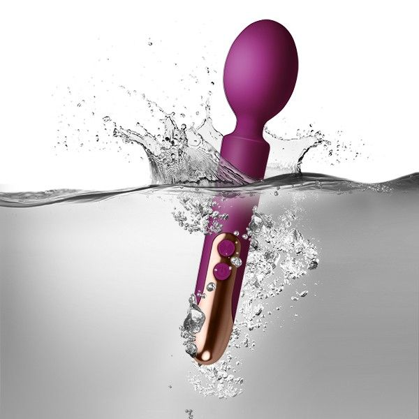 Purple and rose gold electronic device partially submerged in water with water splashes.