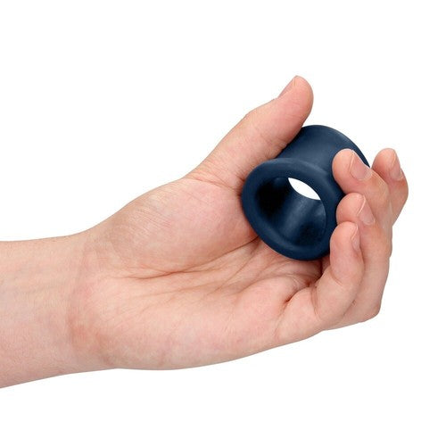Hand holding a blue silicone cock ring against a white background