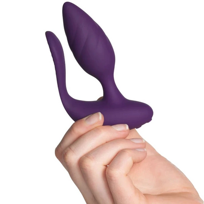 Purple silicone butt plug held by a hand on a white background