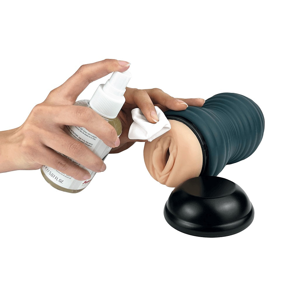 Person applying a product to a masturbator using a spray bottle and cloth on a white background
