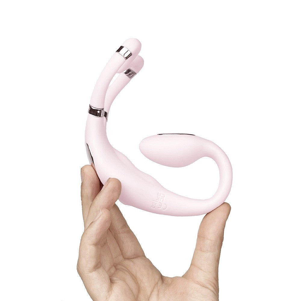 Pink sex toy held in a hand against a white background