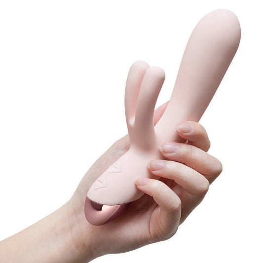 Hand holding a pink silicone rabbit vibrator against a white background