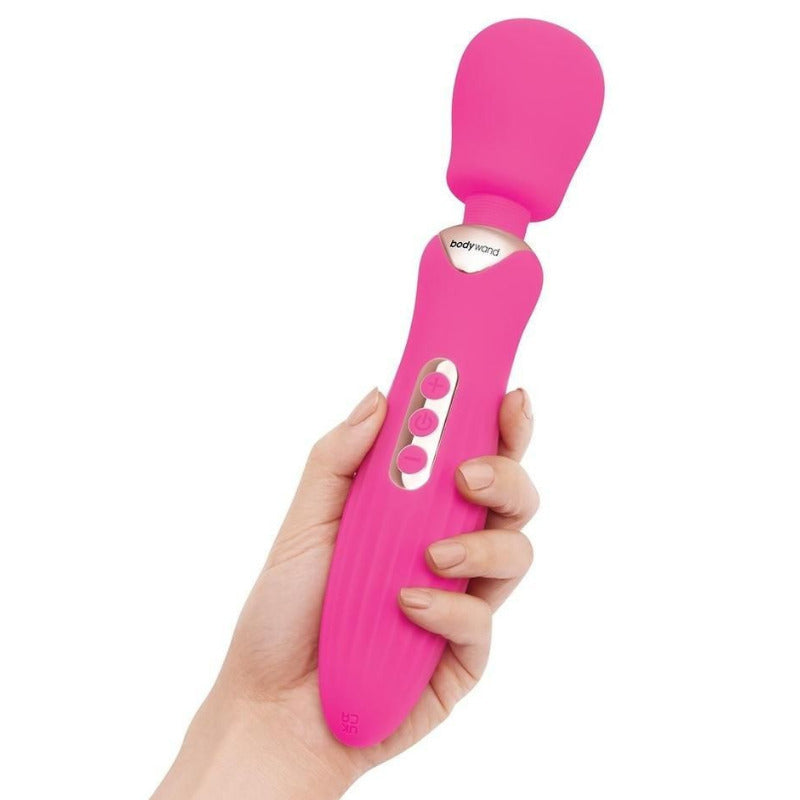 Pink electronic massager held in a hand against a white background