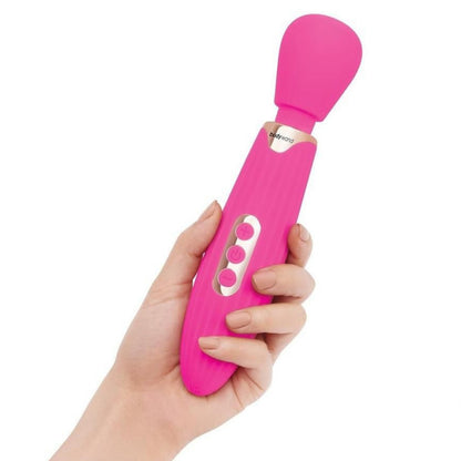 Pink handheld electronic massager held in a hand against a white background