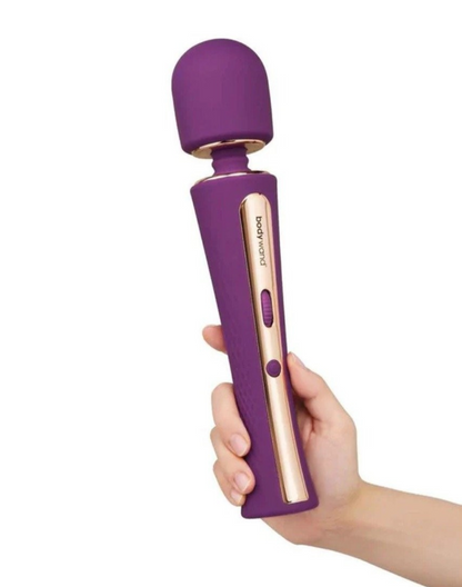 Purple and rose gold handheld vibrator held by a hand on a white background