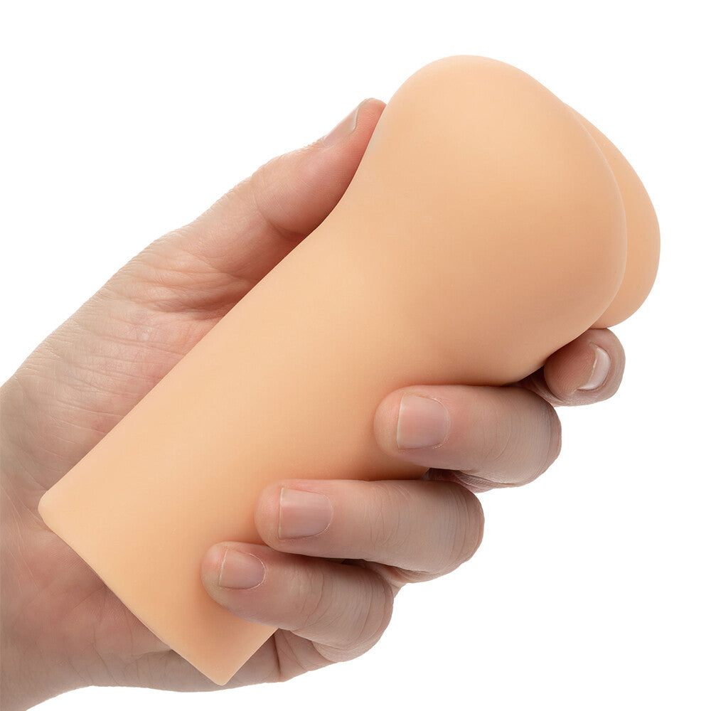Hand holding a peach-colored silicone stroker sleeve on a white background