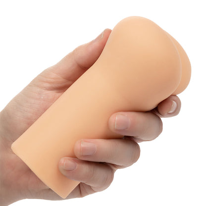 Hand holding a peach-colored silicone stroker sleeve on a white background