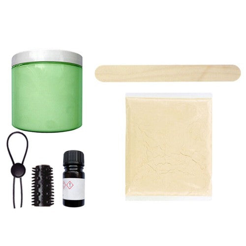 Collection of beauty tools and products including a green container, wooden stick, brush, and essential oil on a white background.