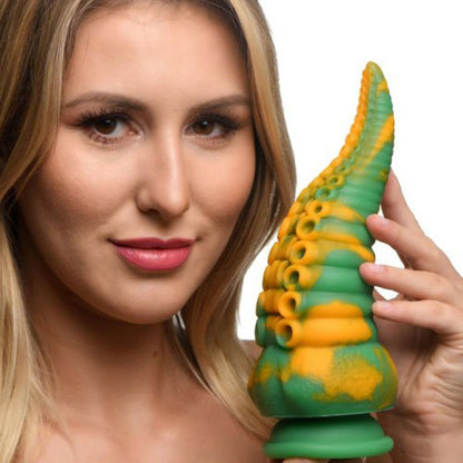 Woman holding a green and orange silicone dildo against a white background