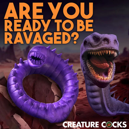 Purple creature cock ring with open mouth and text 'Are you ready to be ravaged?' on a desert landscape background.