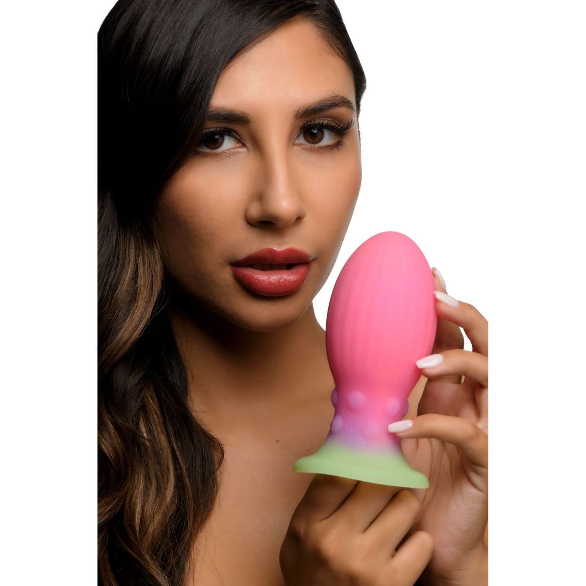 Woman holding a pink and green egg-shaped object against a white background