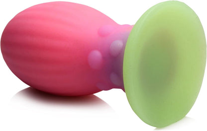 Pink and green silicone buttplug object on a white background
