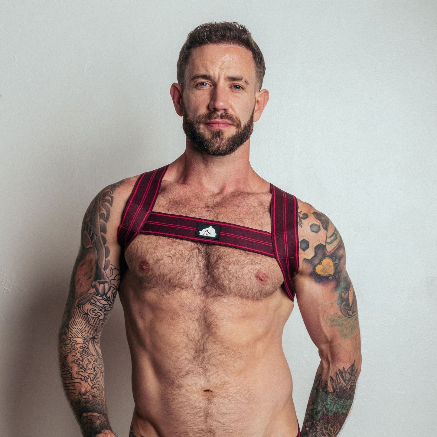 Man wearing a red Adidas sports bra and briefs against a plain background