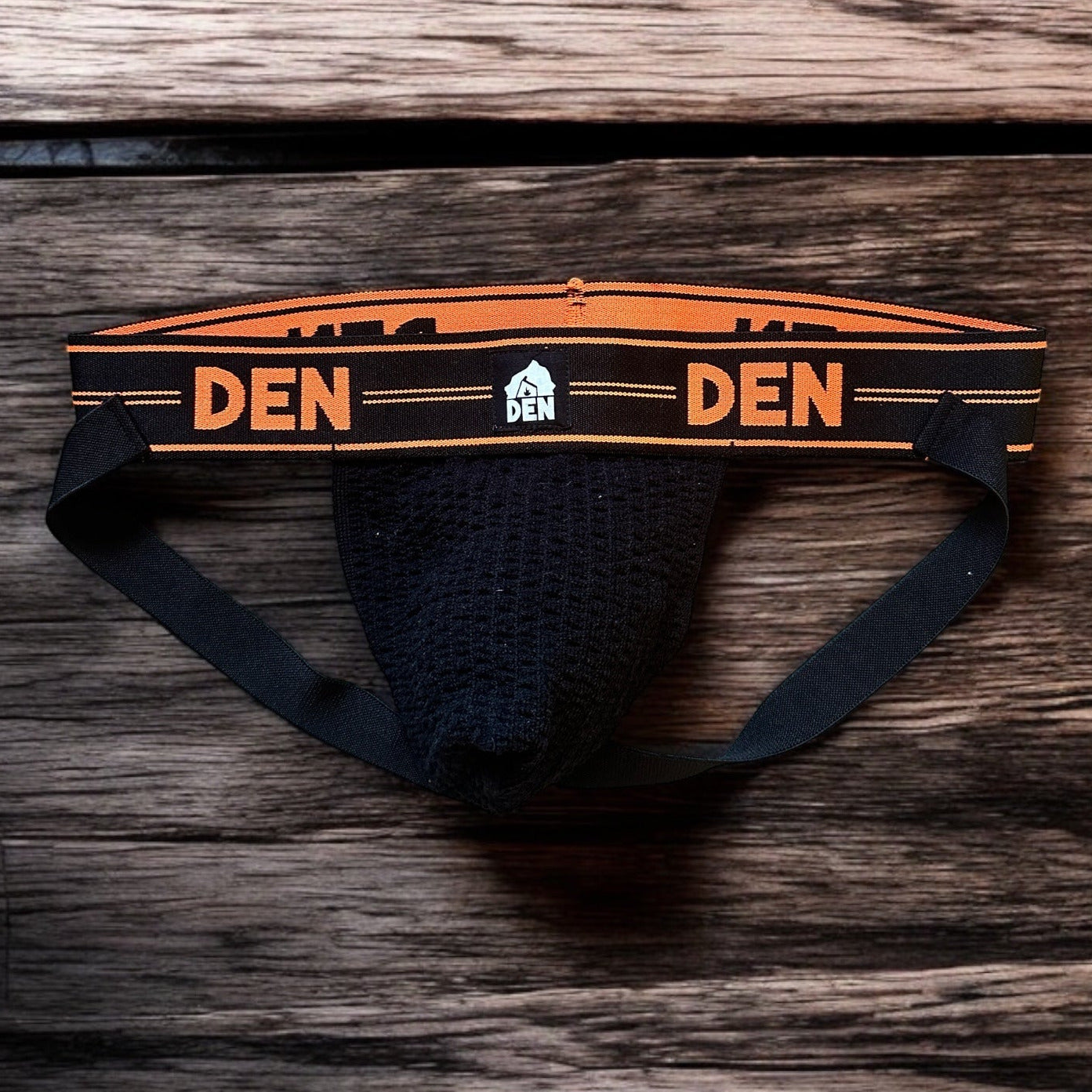 Men's underwear with 'DEN' branding on a wooden surface