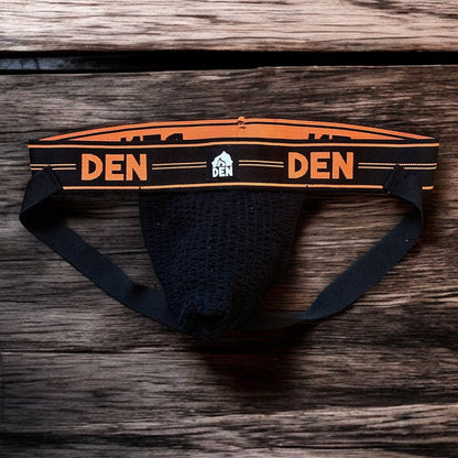 Men's underwear with 'DEN' branding on a wooden surface