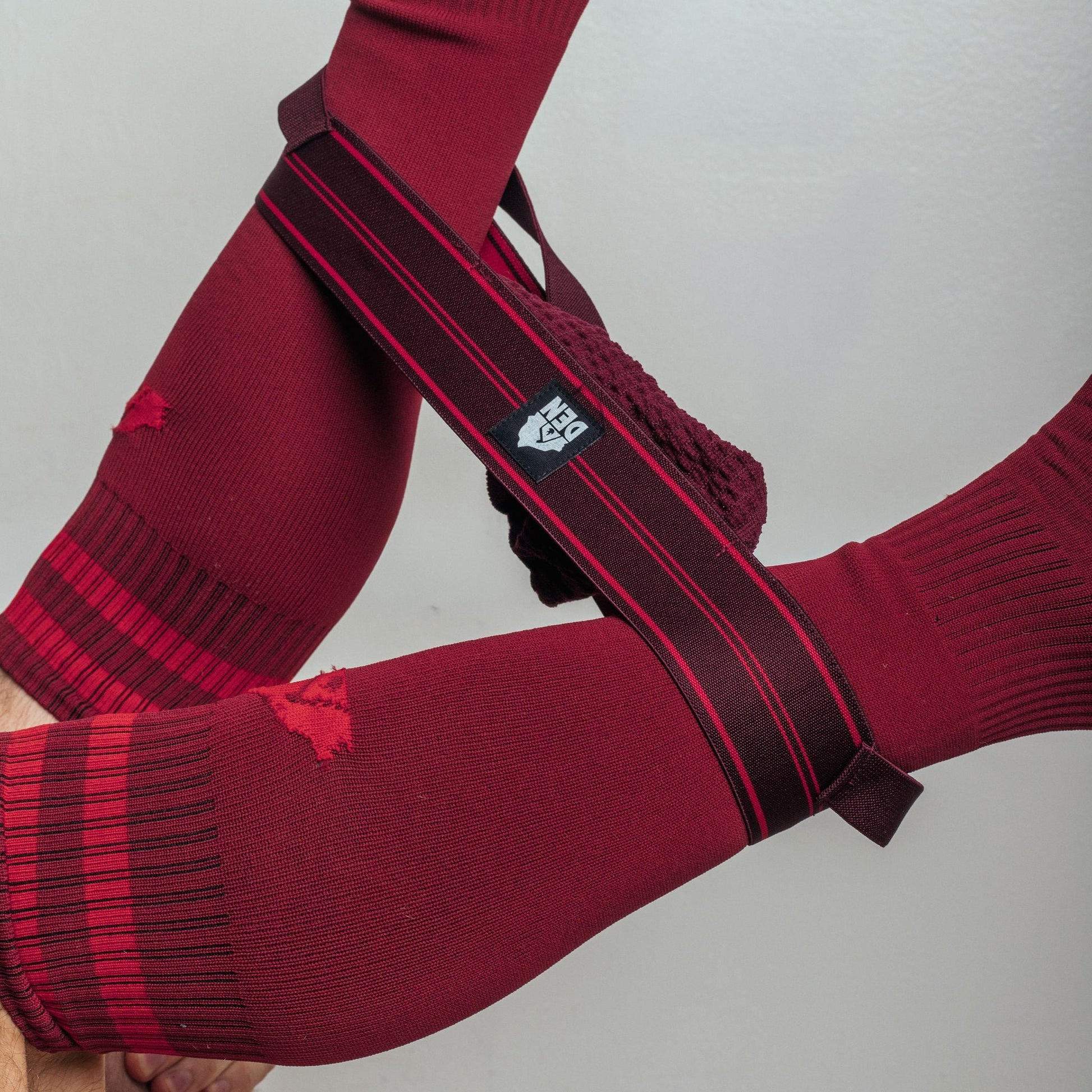 Red sports socks with a black and red band featuring a logo on a light gray background