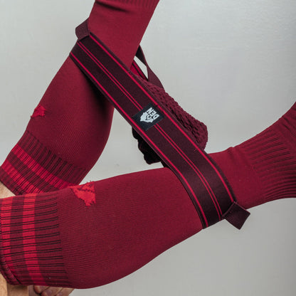 Red sports socks with a black and red band featuring a logo on a light gray background