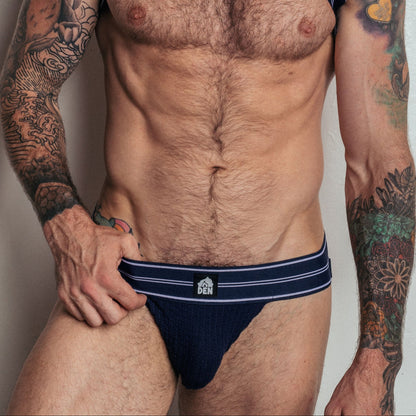 Man wearing navy blue underwear with a white logo on a plain background
