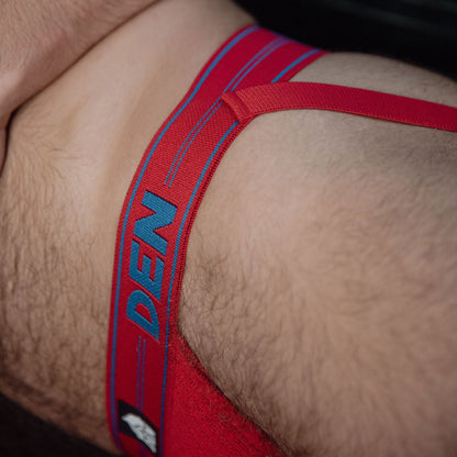 Red men's underwear with 'DEN' branding on a close-up of skin.
