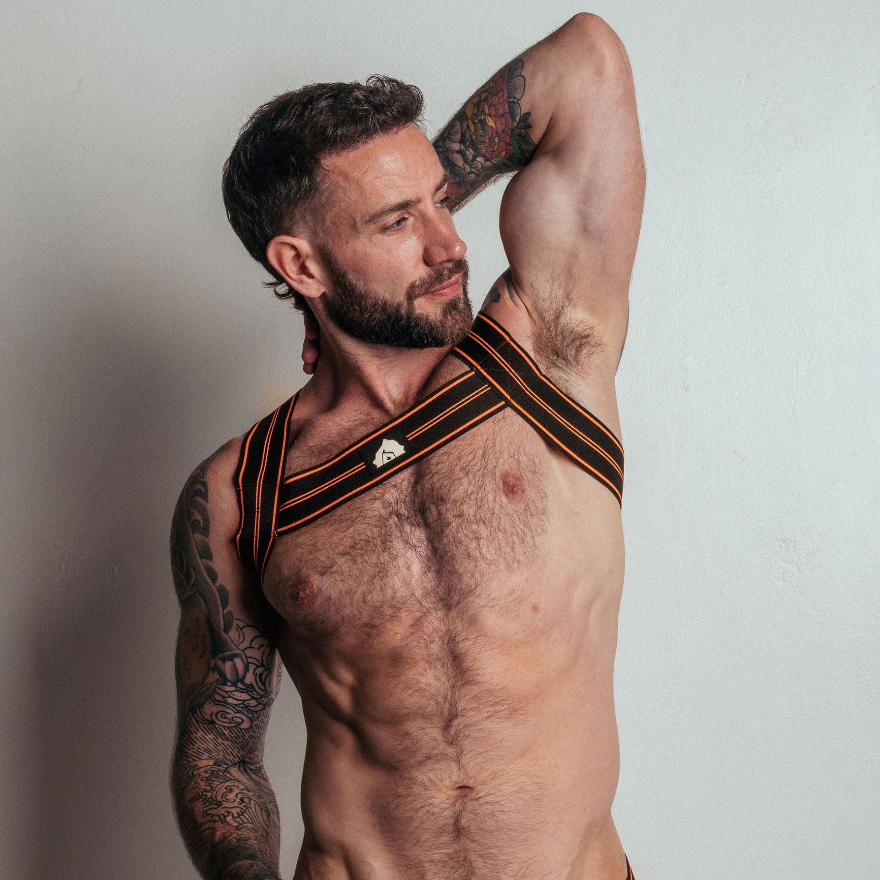 Man wearing a black and orange sports bra and underwear set with 'DEN' branding on a plain background.