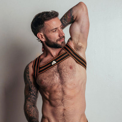 Man wearing a black and orange sports bra and underwear set with 'DEN' branding on a plain background.