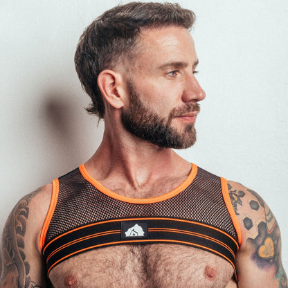 Man wearing a black and orange mesh tank top against a plain background