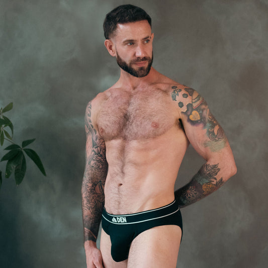 Man wearing a black DEN brief against a gray background