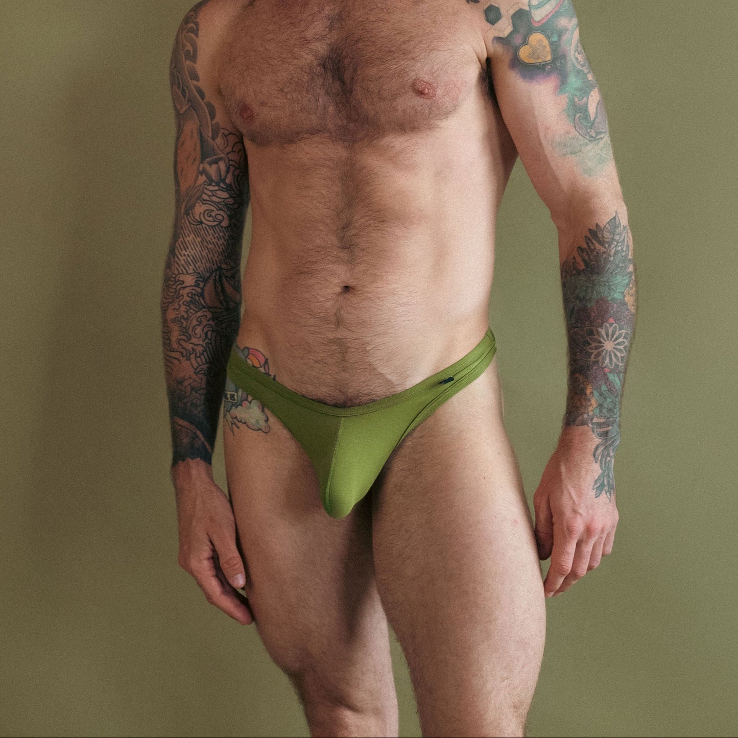 Man wearing a green thong against a plain background