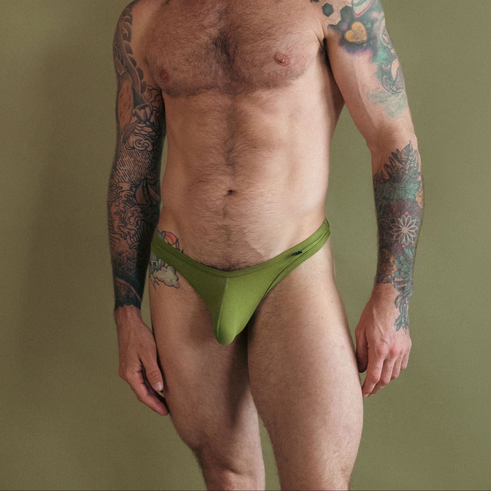 Man wearing a green thong against a plain background