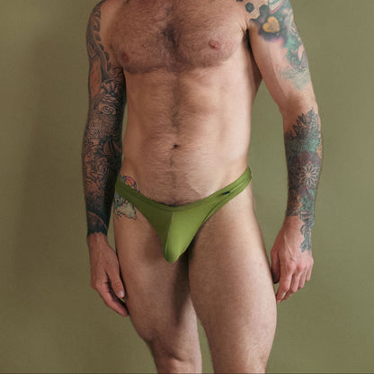 Man wearing a green thong against a plain background