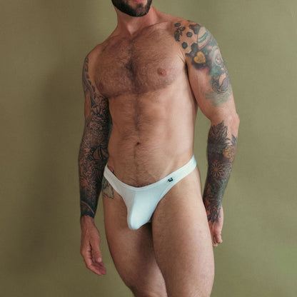 Man wearing a white thong against a plain background