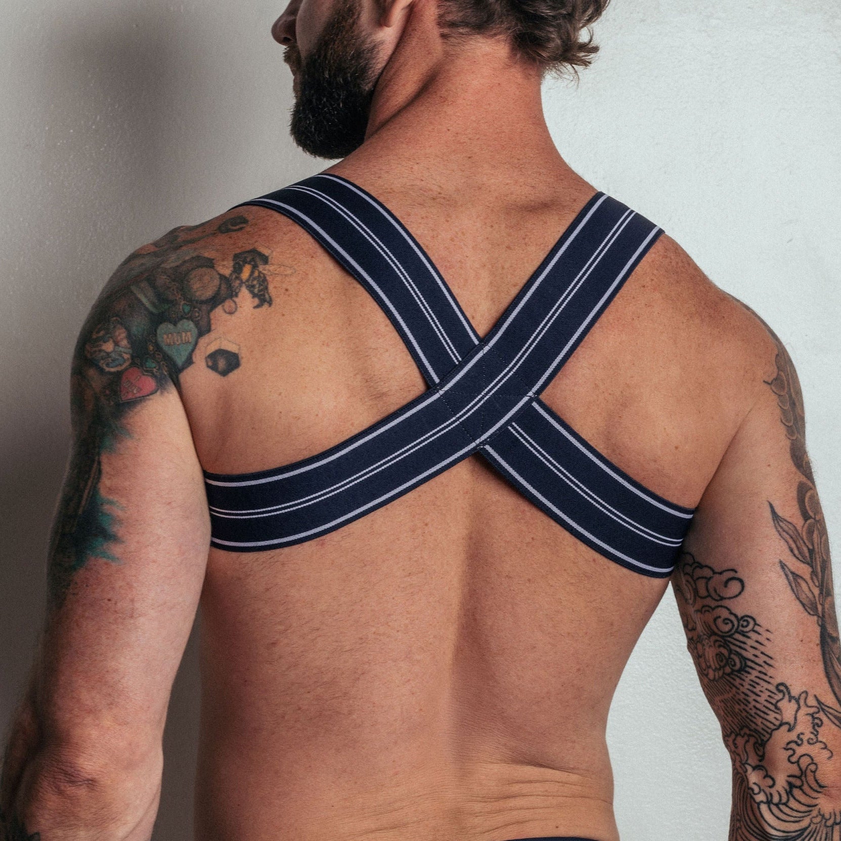 Man wearing a black and blue striped thong against a plain background