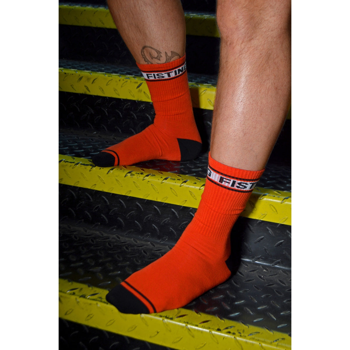 Red socks with black accents worn on a person's feet, standing on a metallic surface.