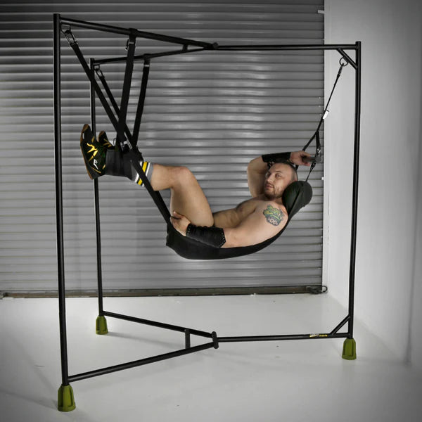 Person using a black sex swing in a room with a metal shutter.