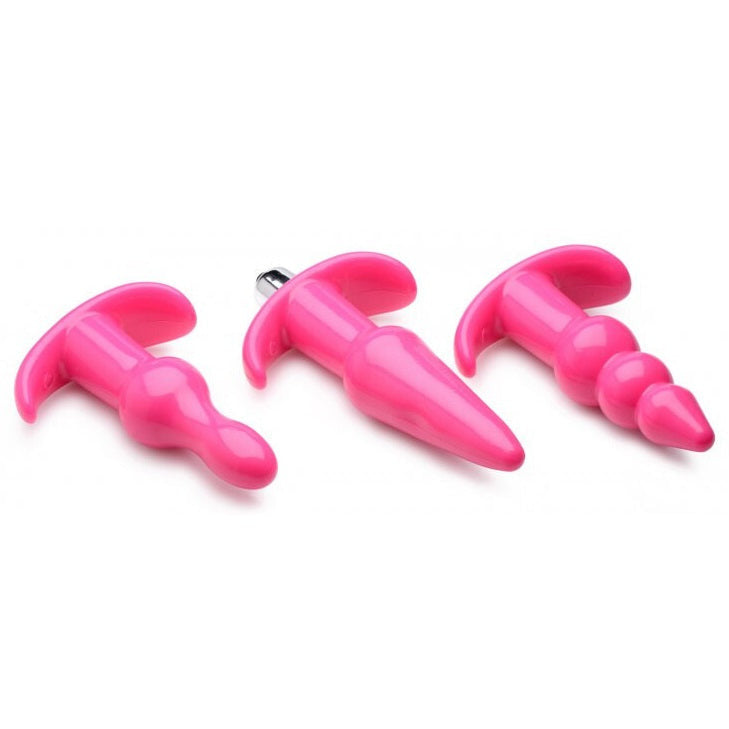 Three pink silicone butt plugs of different sizes on a white background