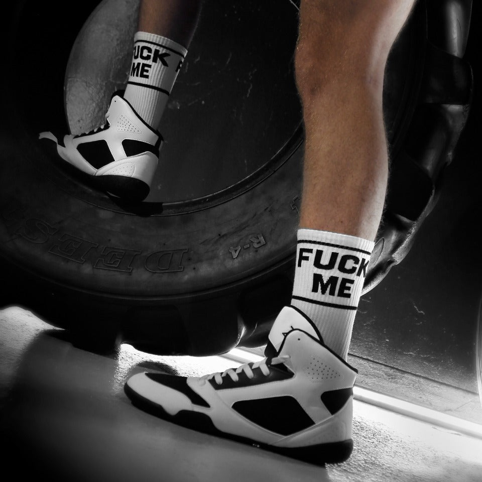 Person wearing 'Fuck Me' socks lifting a tire