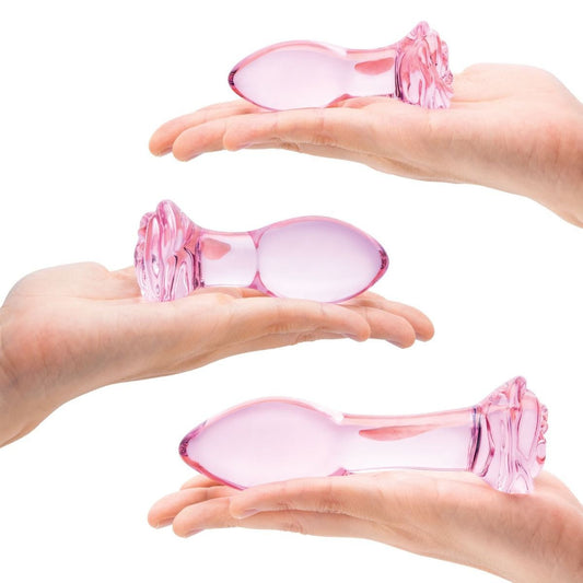 Three hands holding pink glass objects against a white background
