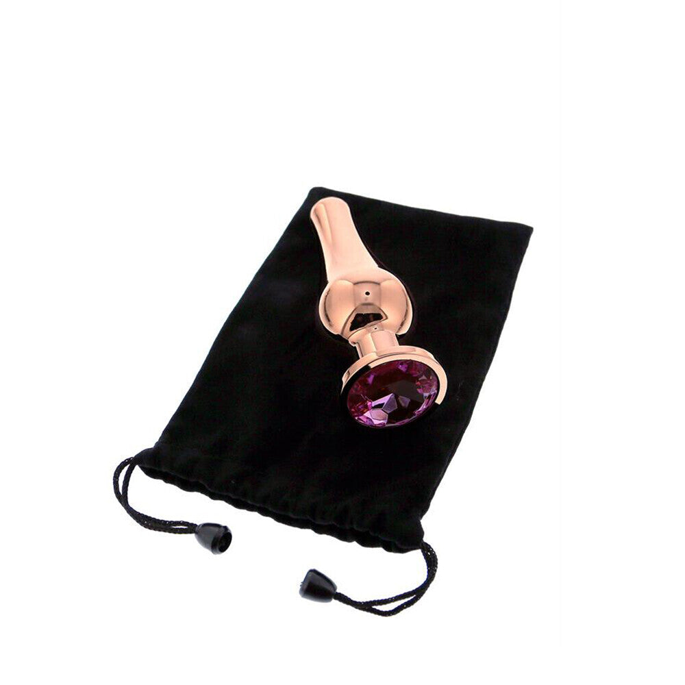 Rose gold and purple gemstone object on a black drawstring bag against a white background