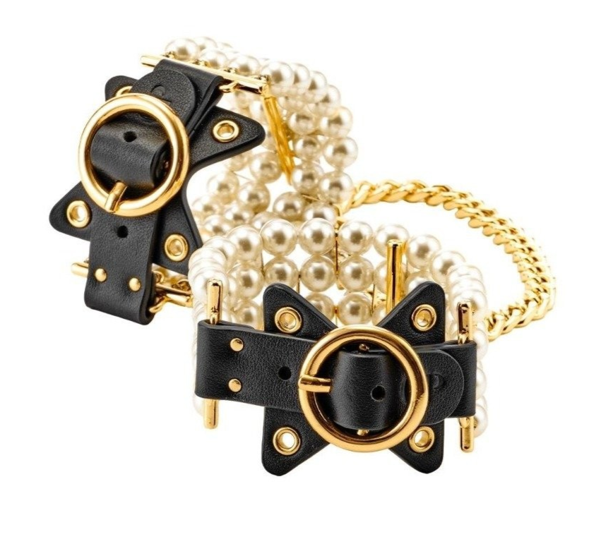 Black cuffs with gold accents and pearls on a white background
