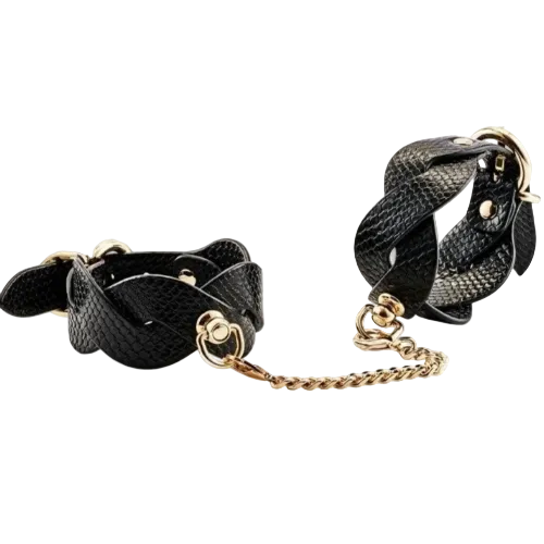 Black leather cuffs with gold chain links on a white background