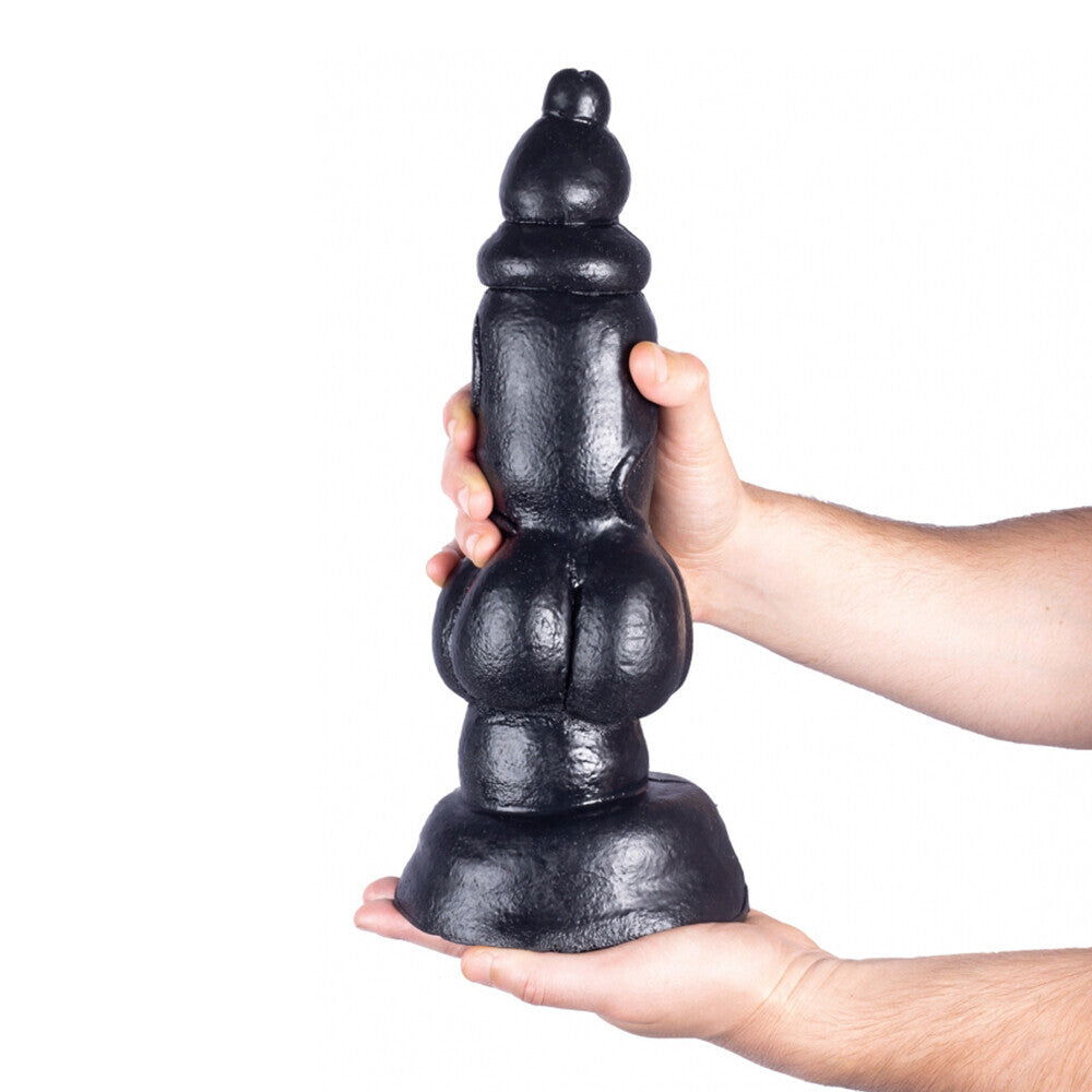 Hand holding a large black dildo against a white background