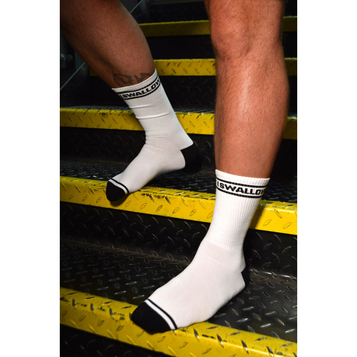 White socks with black accents worn by a person on a metallic surface.