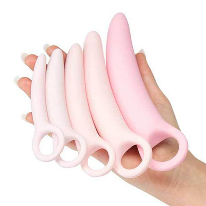 Pink silicone utensils held in a hand against a white background