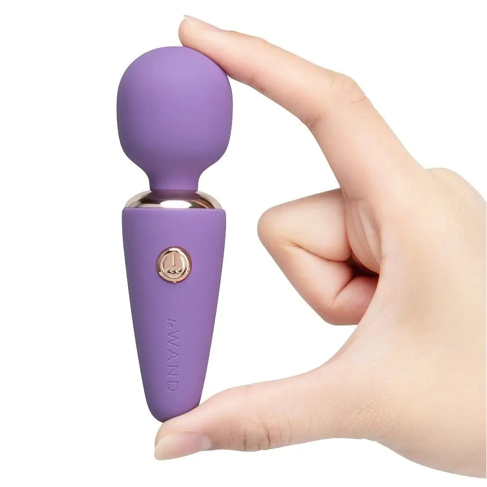 Purple handheld massager held in a hand against a white background