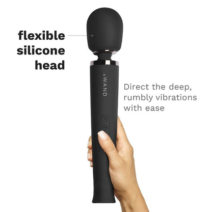 Black handheld device with flexible silicone head held by a hand on a white background