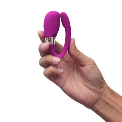 Hand holding a purple silicone vibrator with a white background
