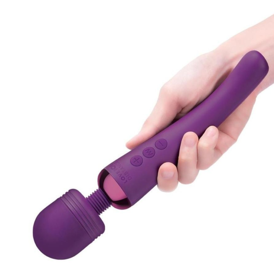 Hand holding a purple handheld massage wand on a white background