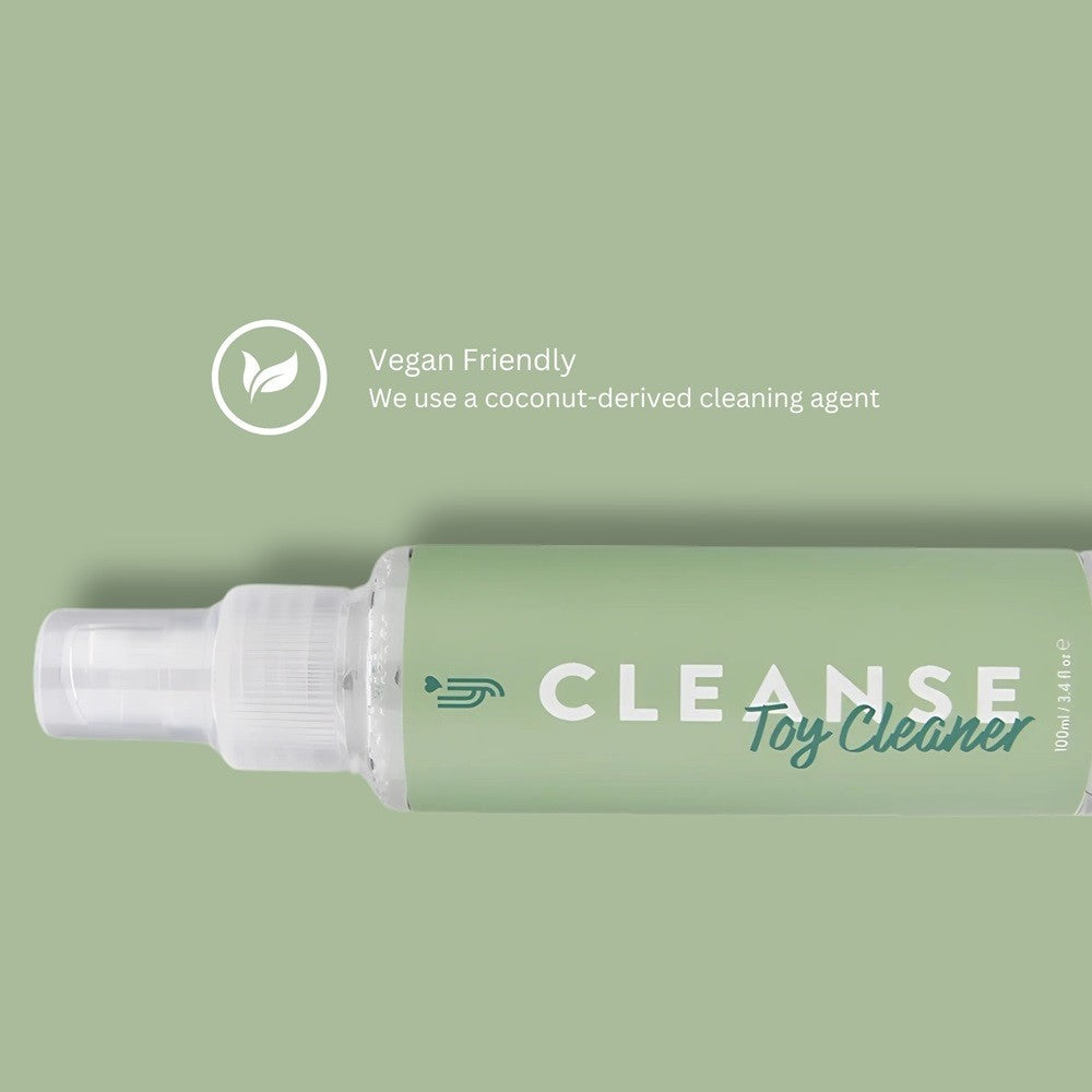 Green bottle of 'CLEANSE Toy Cleaner' with a coconut-derived cleaning agent label on a green background