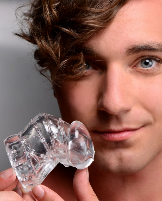 Man holding a clear male chastity device against a neutral background